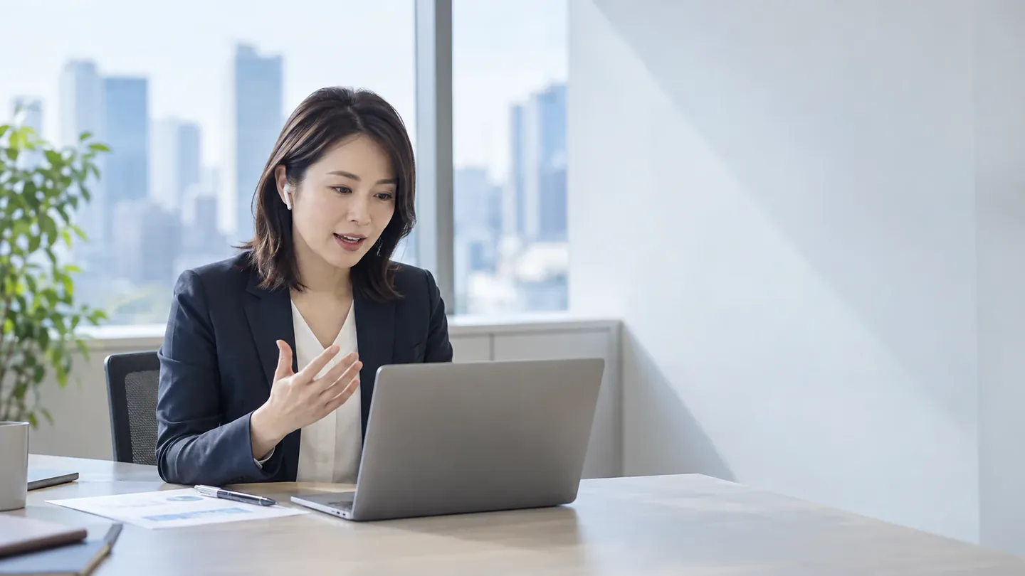 オフィスでノートパソコンに向かって話している女性